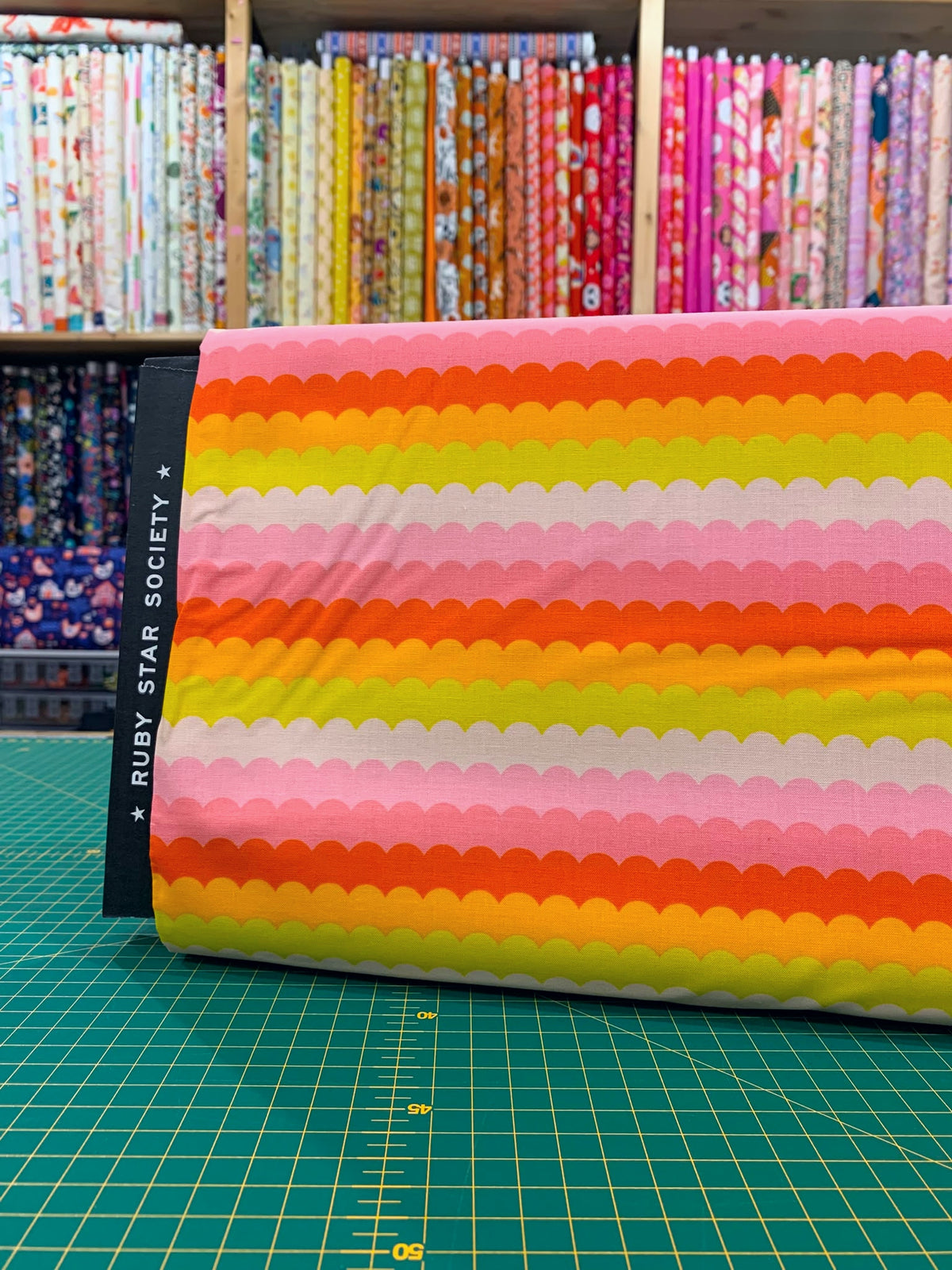 Dettaglio tessuto cotone americano arancione e rosa Poolside Too Scallops con stampe geometriche a onde retrò per cucito creativo.