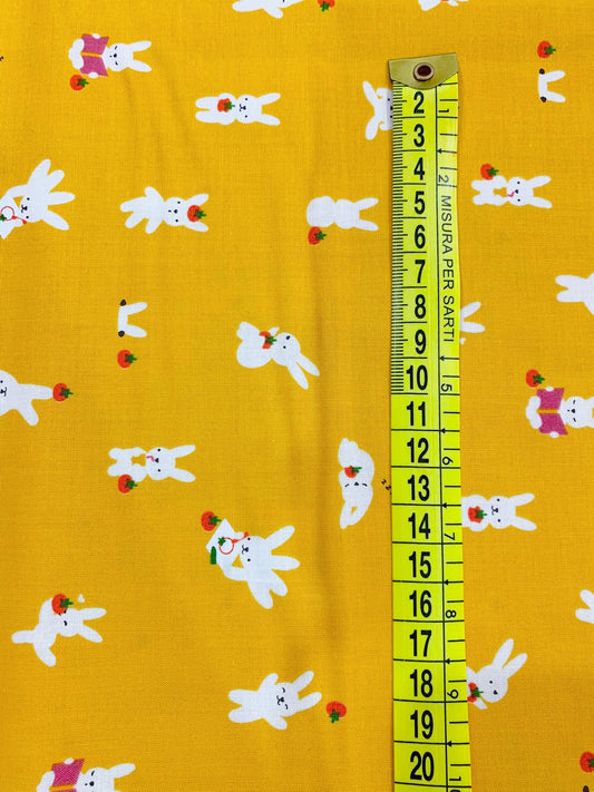Dettaglio misura stampa tessuto cotone americano giallo senape Persimmon con stampe di simpatici coniglietti bianchi