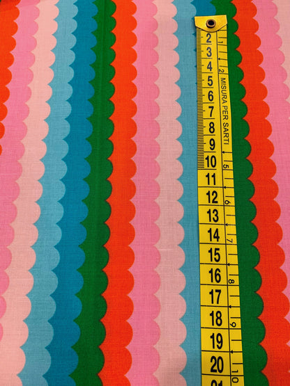 Dettaglio misura stampa tessuto cotone americano verde e arancione Poolside Too Scallops con stampe geometriche a onde retrò per cucito.