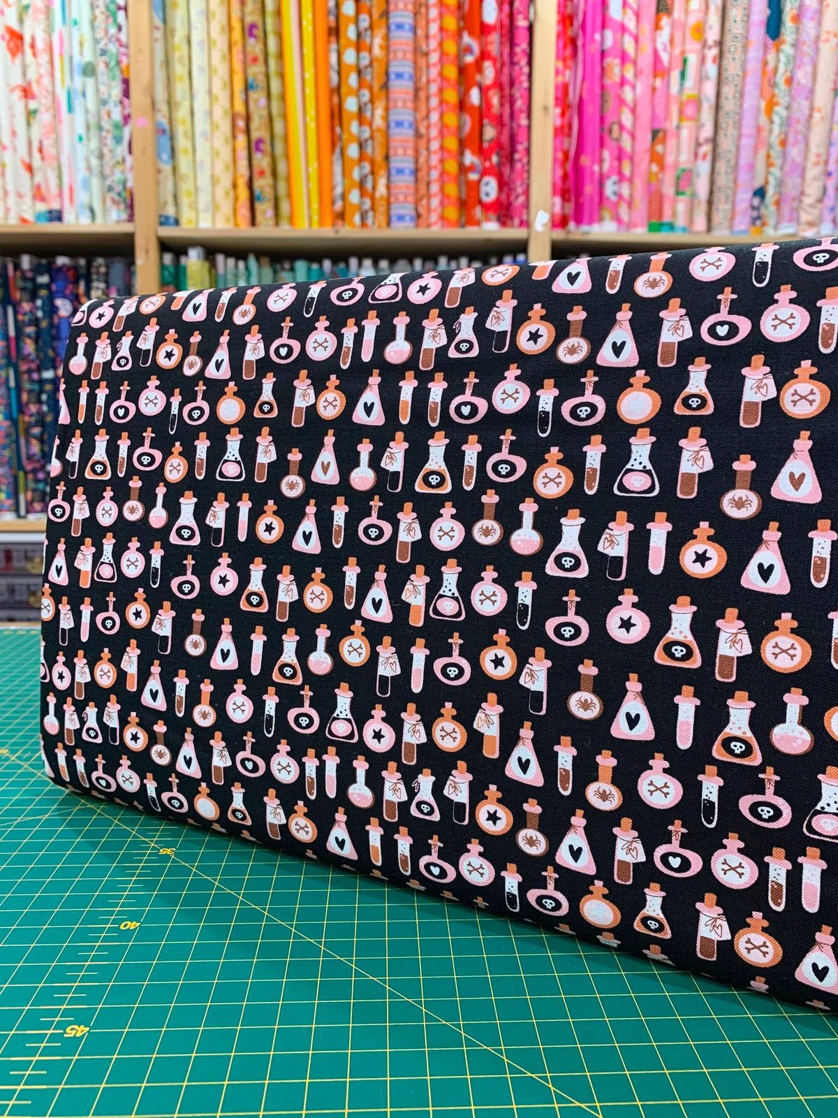 Dettaglio tessuto cotone americano arancione pastello Moda Fabrics Purrs And Boos con micro stampe di boccette di pozione magica e ampolle.