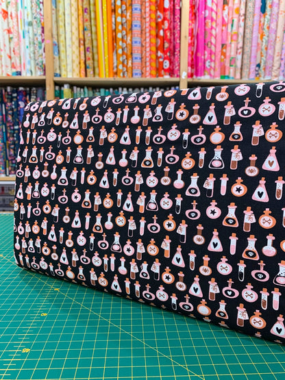 Dettaglio tessuto cotone americano arancione pastello Moda Fabrics Purrs And Boos con micro stampe di boccette di pozione magica e ampolle.