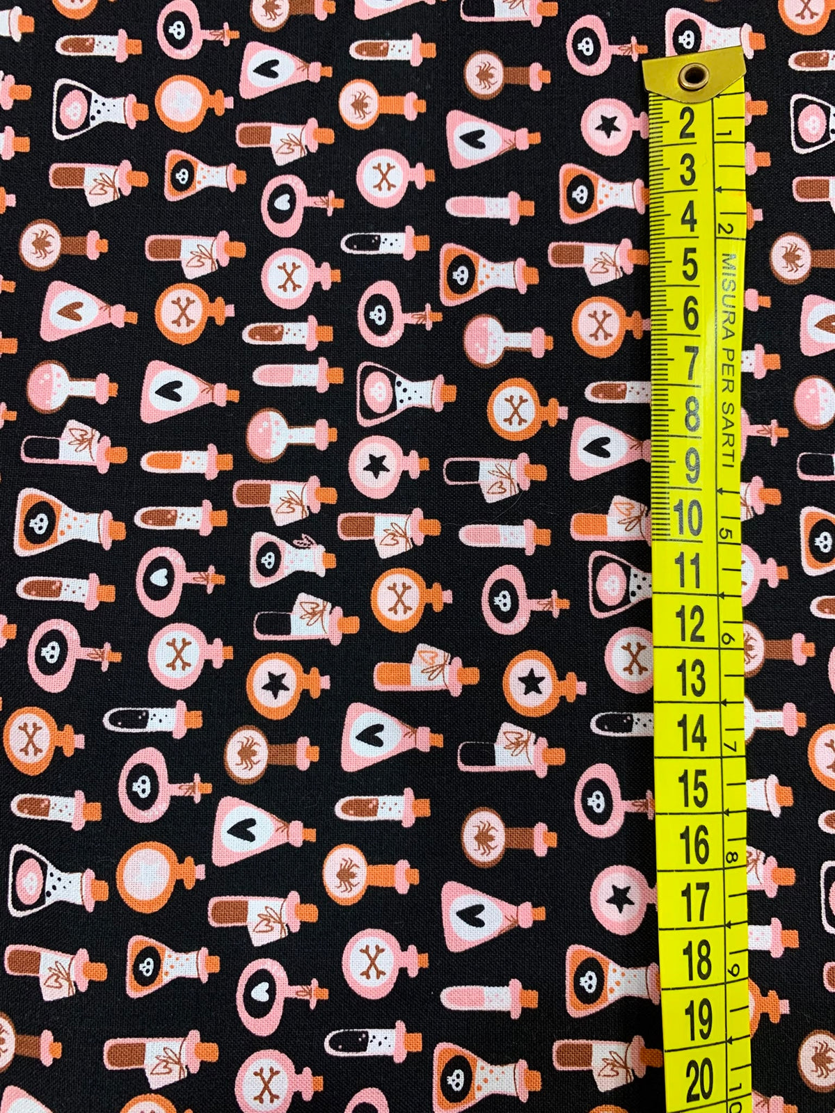 Dettaglio misura tessuto cotone americano arancione pastello Moda Fabrics Purrs And Boos con micro stampe di boccette di pozione magica e ampolle.