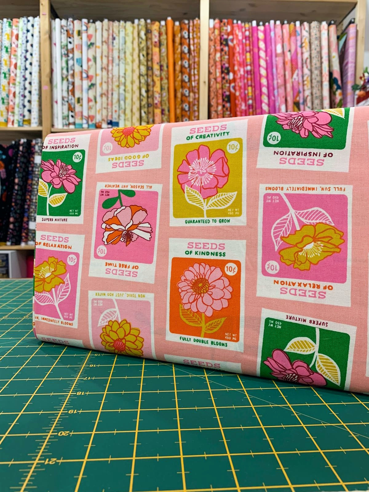 Tessuto cotone americano rosa Seeds Novelty Garden con stampe grafiche di bustine di semi vintage e scritte d'epoca per cucito creativo.